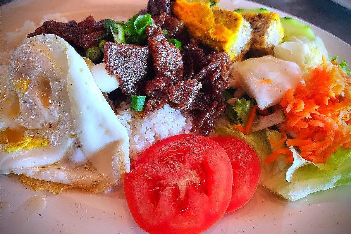 A Vietnamese rice plate with grilled meat, a fried egg, tomato slices and pickled carrots at Mama Kim's in Nederland