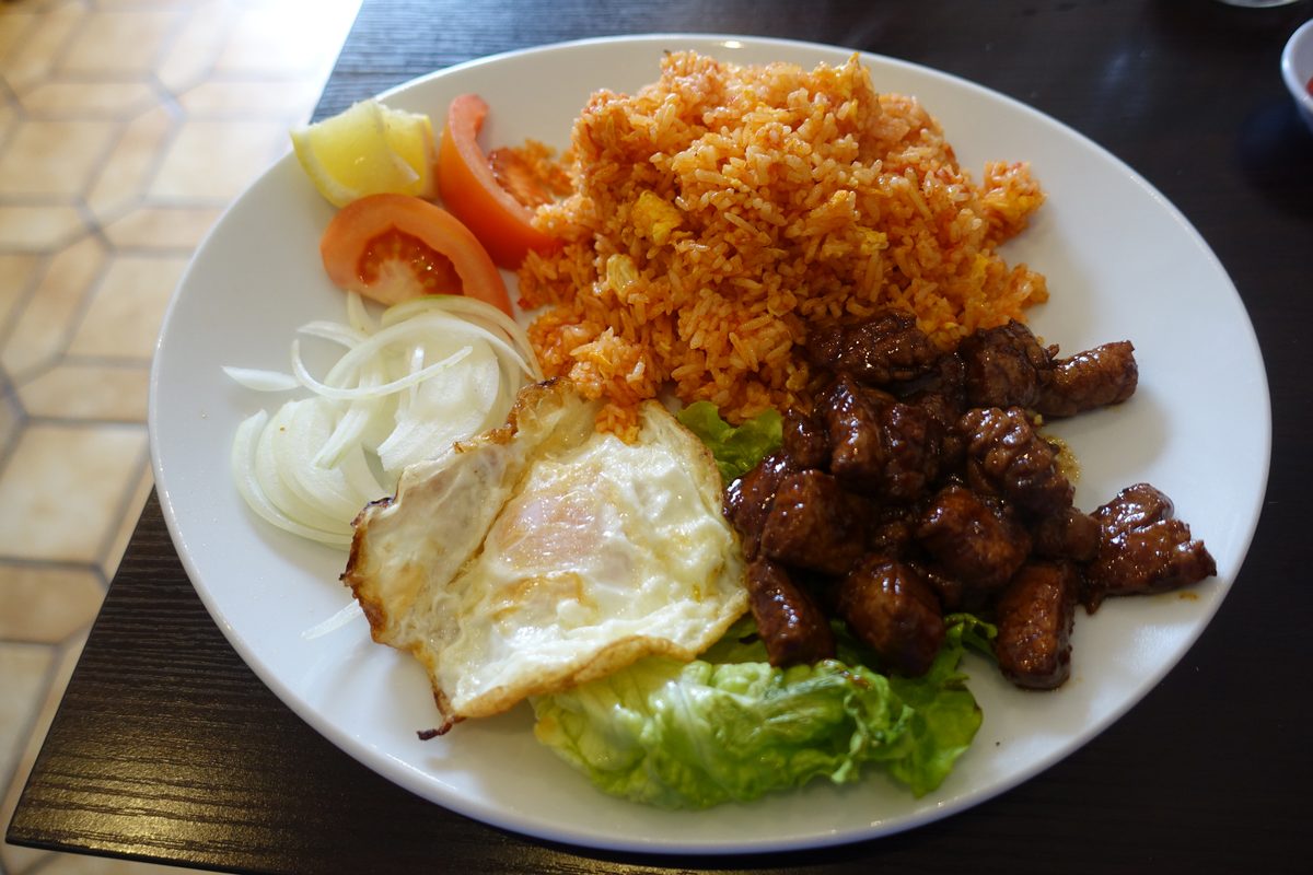 Shaken beef with tomato rice, a fried egg, sliced onion and lettuce